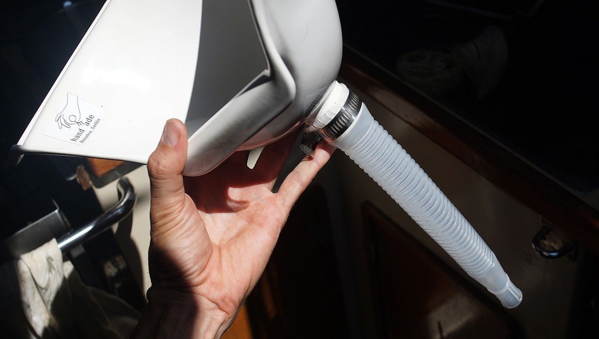 A photo of a hand holding a urine diverter with its drain tube attached