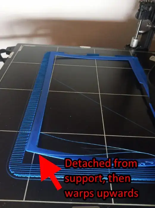 Photo of the printed model on the build plate with corners curled up