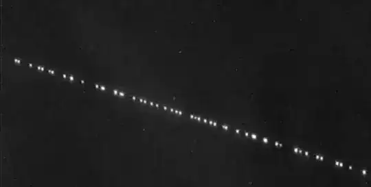 Starlink satellites are seen streaking across the sky like tiny white dots.