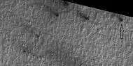 Close view of defrosting, as seen by HiRISE under HiWish program. Gas and dark dust is probably being blown out of ground and then carried by winds toward the Northwest.  Arrow points to a possible spider formation.