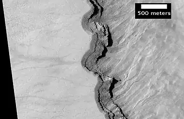 Close-up of layers in west slope of Asimov Crater.  Shadows show the overhang.  Some of the layers are much more resistant to erosion, so they stick out.  Image from HiRISE.