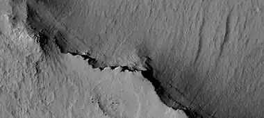 Close view of cap rock, as seen by HiRISE  The cap rock overhangs some layers.  The cap rock was more resistant to erosion, so it formed an overhang.