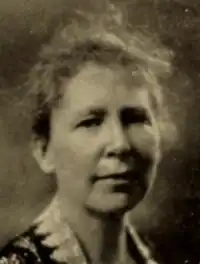 A middle-aged white woman wearing a collared jacket with lace trim