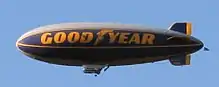 Cigar-shaped blimp with "Good Year" written on its side.