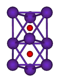 The ball-and-stick diagram shows two regular octahedra which are connected to each other by one face. All nine vertices of the structure are purple spheres representing rubidium, and at the centre of each octahedron is a small red sphere representing oxygen.