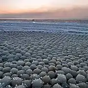Ice eggs gain spherical symmetry by being rolled about by wind and currents.