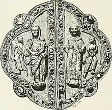 An ornate piece of metal with human figures standing on it embossed